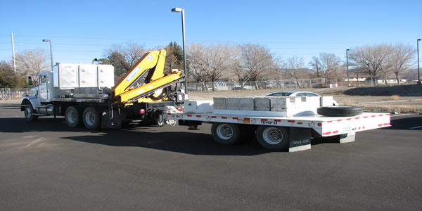 Flat bed truck with loader pulling trailer